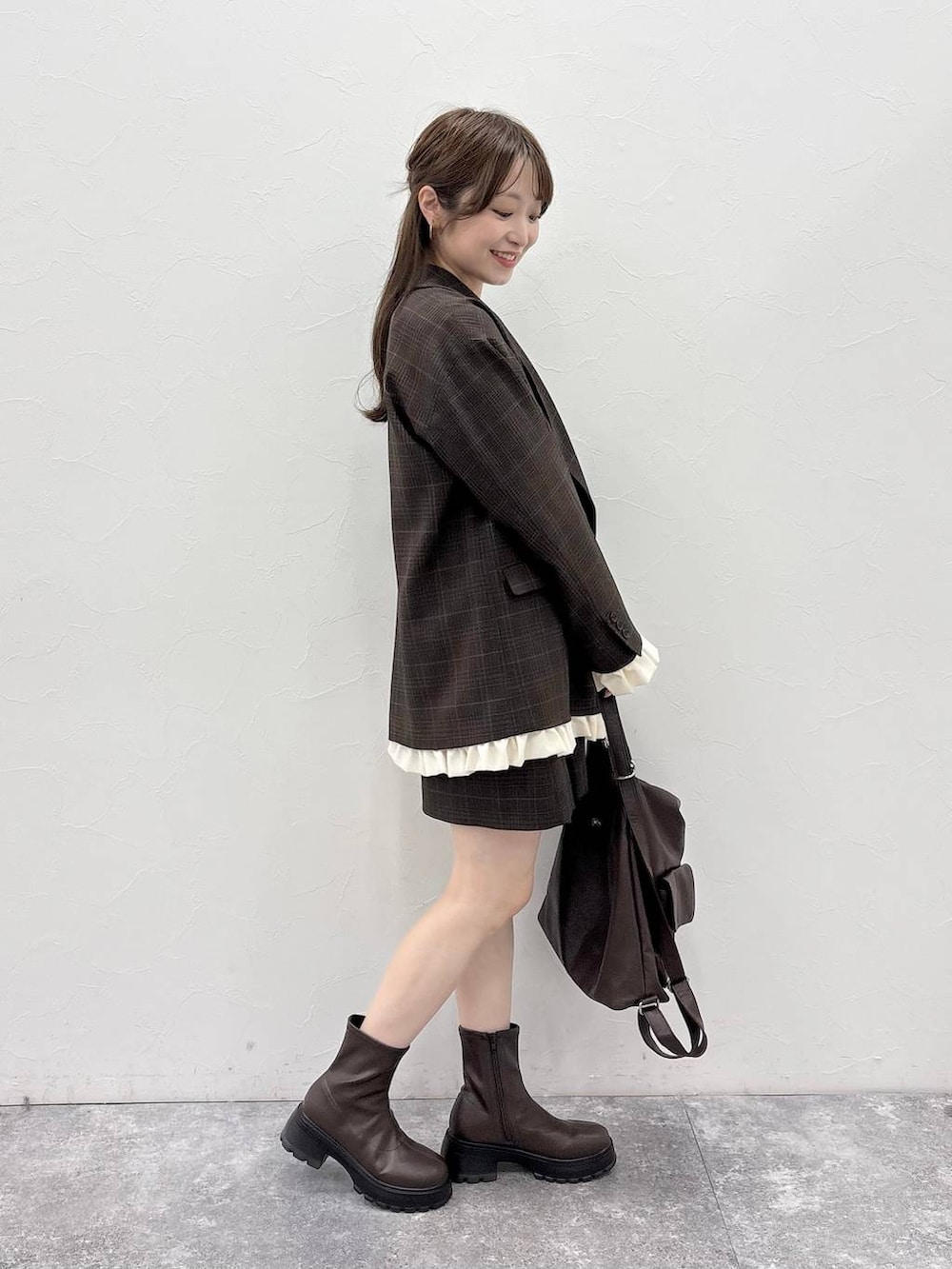 ブラウン系のブーツ、ブラウン系のバックパック/リュック、ホワイト系のTシャツ/カットソーを着用したレディースの秋コーディネートの2枚目の写真