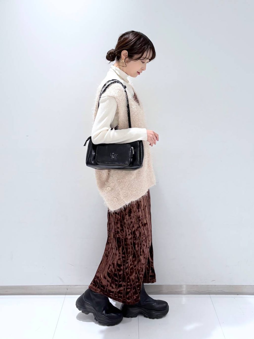 ホワイト系のニット/セーター、ブラック系のショルダーバッグ、ブラック系のブーツを着用したレディースの冬コーディネートの3枚目の写真