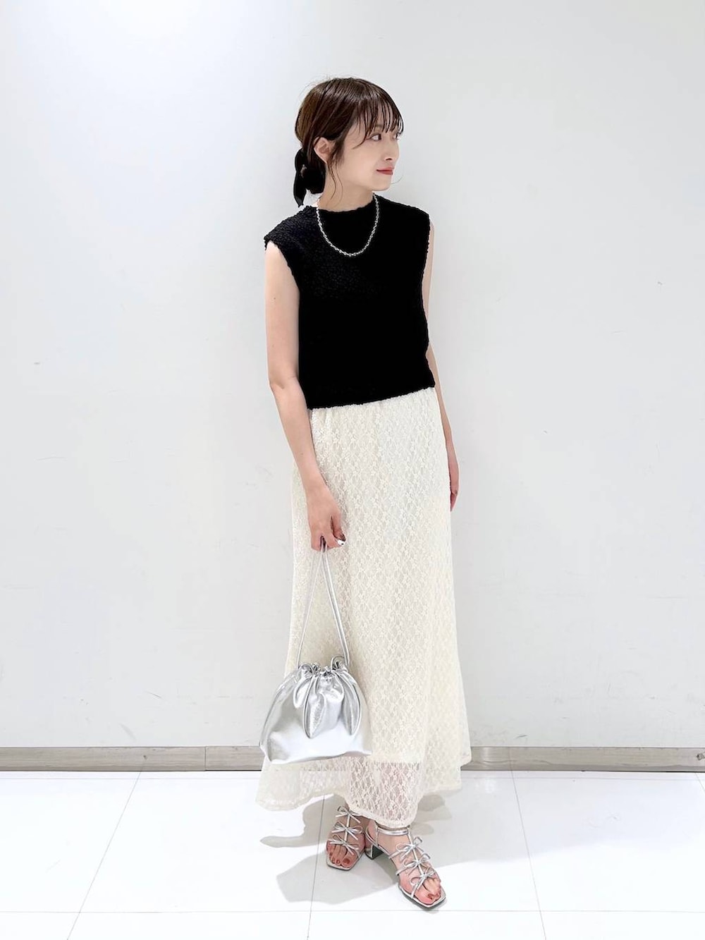 シルバー系のサンダル、ホワイト系のスカート、ブラック系のベストを着用したレディースの夏コーディネートの3枚目の写真
