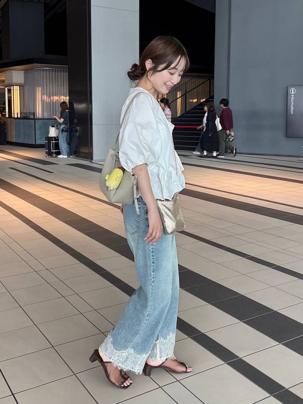 ゴールド系のショルダーバッグ、ブルー系のデニムパンツ、ホワイト系のシャツ/ブラウスを着用したレディースの夏コーディネートの3枚目の写真