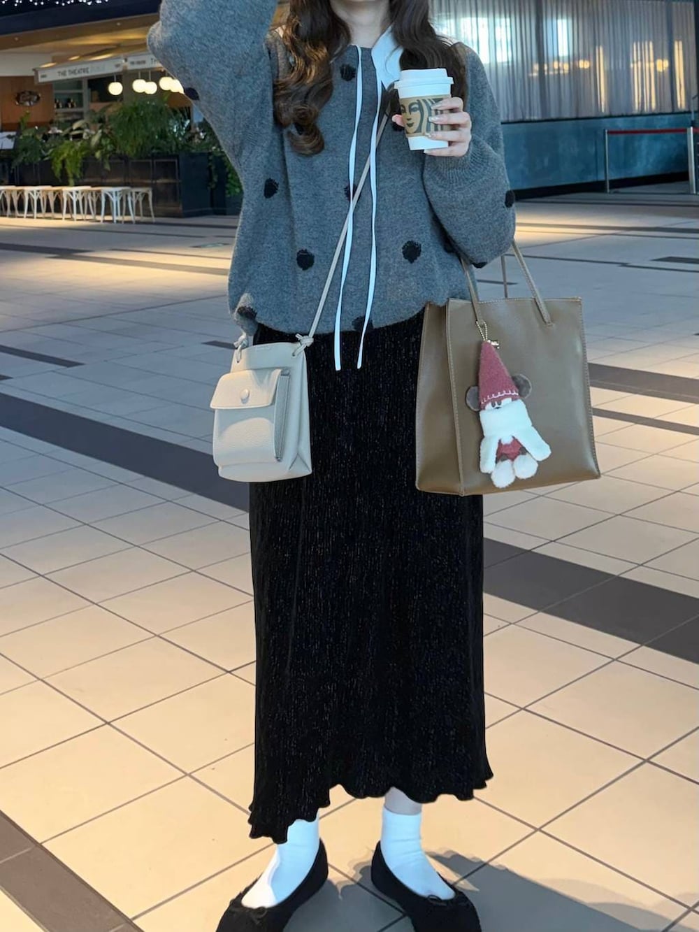 ブラック系のスカート、ホワイト系のシャツ/ブラウス、グレー系のニット/セーターを着用したレディースの冬コーディネートの2枚目の写真