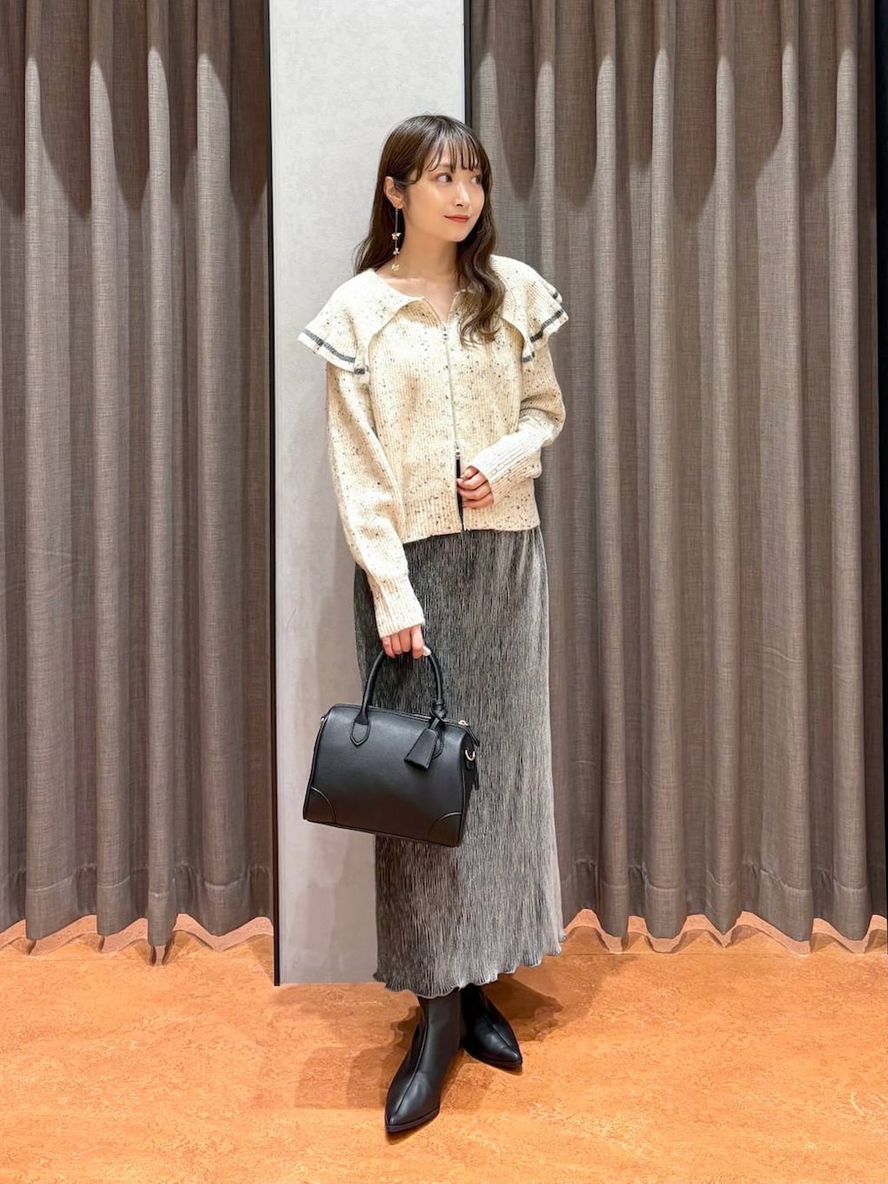 ブラック系のショルダーバッグ、ベージュ系のニット/セーター、グレー系のスカートを着用したレディースの秋コーディネートの3枚目の写真