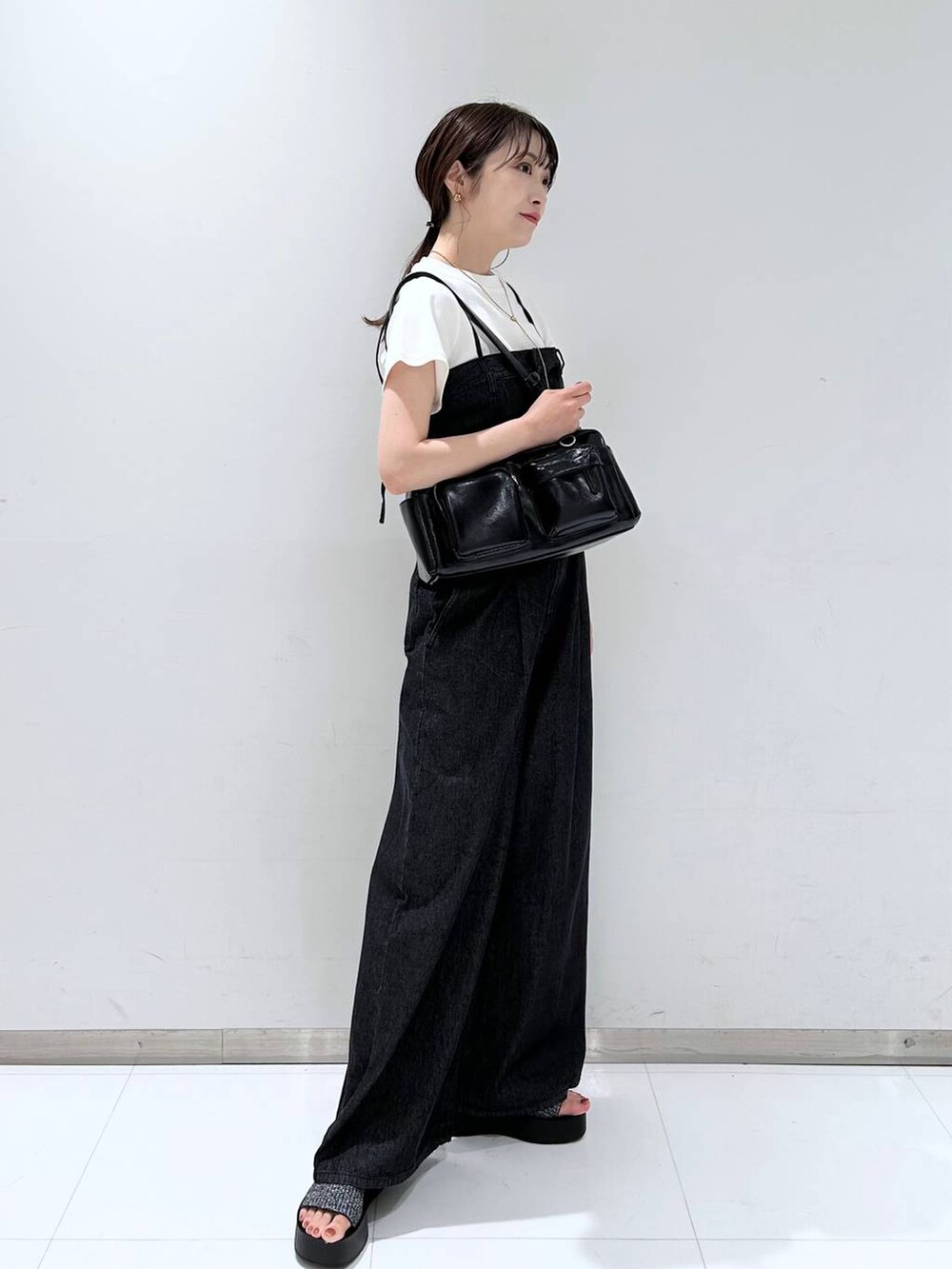 ブラック系のサンダル、ホワイト系のTシャツ/カットソー、ブラック系のボストンバッグを着用したレディースの夏コーディネートの3枚目の写真