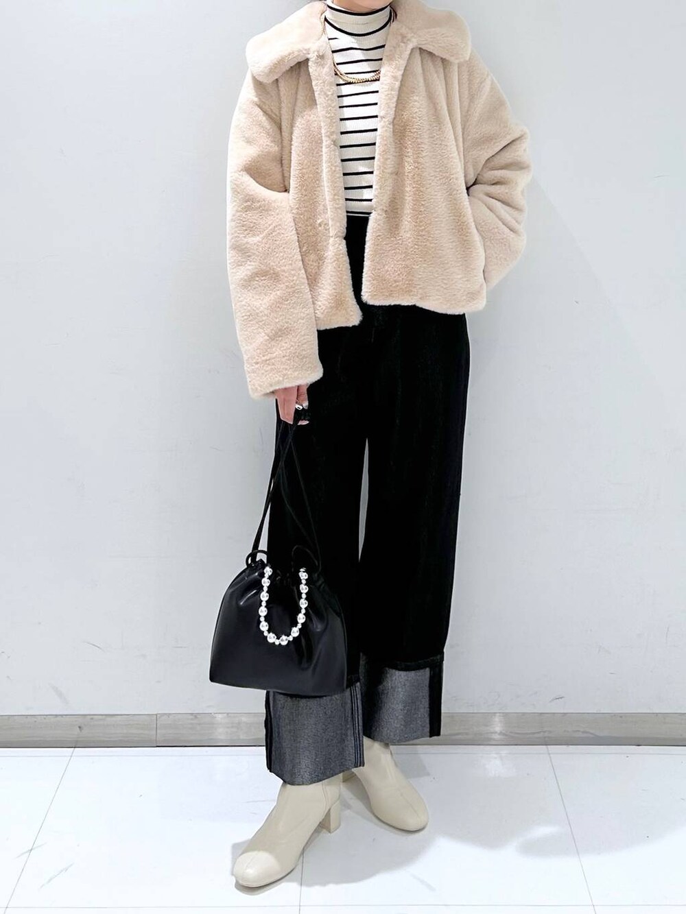 その他のニット/セーター、ホワイト系のブーツ、ブラック系のショルダーバッグを着用したレディースの秋コーディネートの2枚目の写真