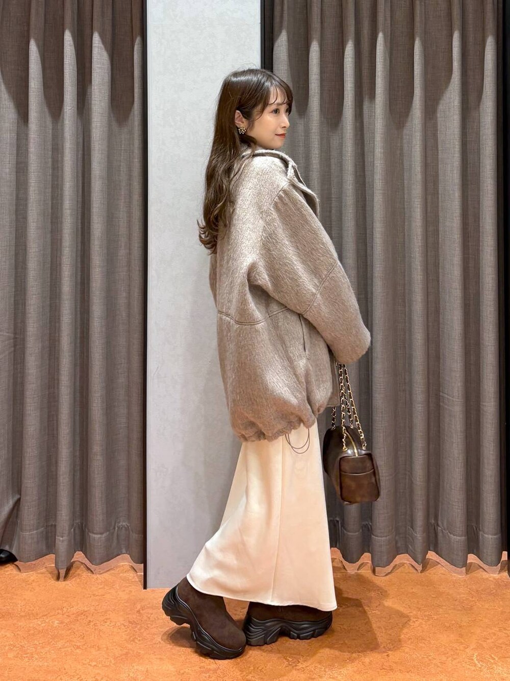 ブラウン系のブーツ、ホワイト系のスカート、ホワイト系のその他アウターを着用したレディースの冬コーディネートの3枚目の写真