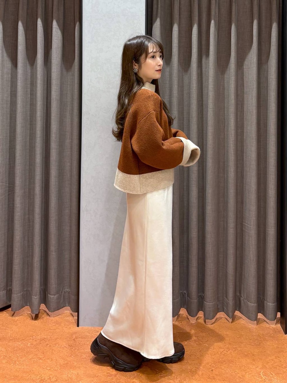 ブラウン系のブーツ、ホワイト系のスカート、ホワイト系のその他アウターを着用したレディースの冬コーディネートの6枚目の写真