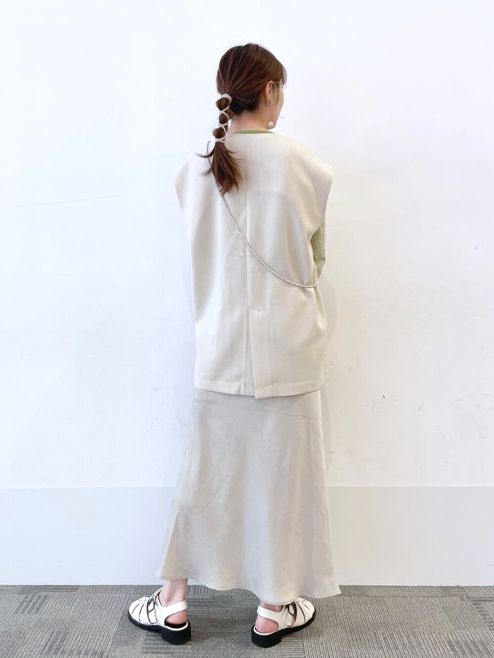 ホワイト系のサンダル、ホワイト系のスカート、グリーン系のショルダーバッグを着用したレディースの春コーディネートの2枚目の写真