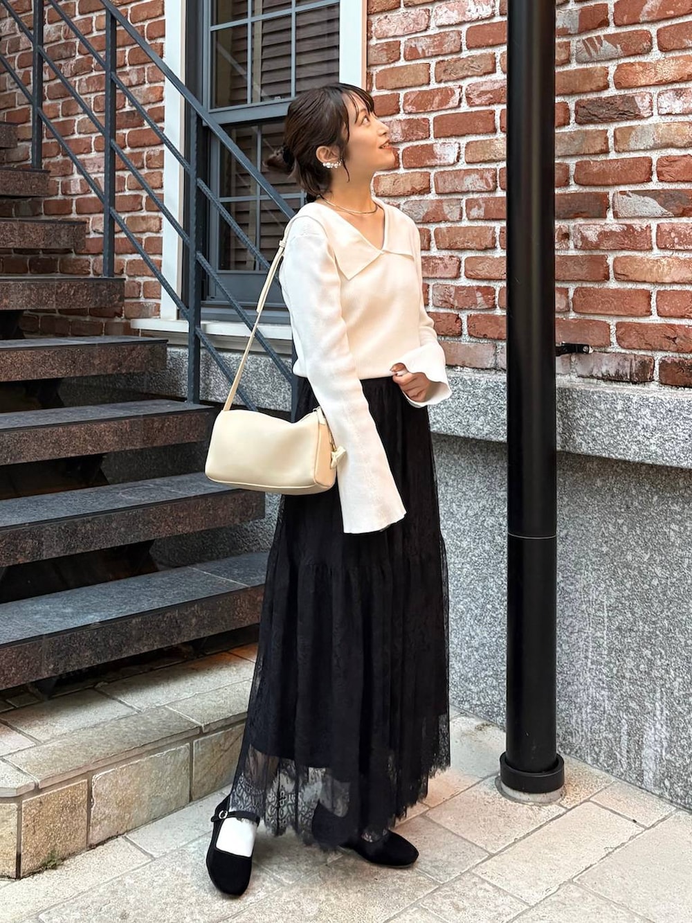 ベージュ系のハンドバッグ、ホワイト系のニット/セーター、シルバー系のチョーカーを着用したレディースの秋コーディネートの3枚目の写真