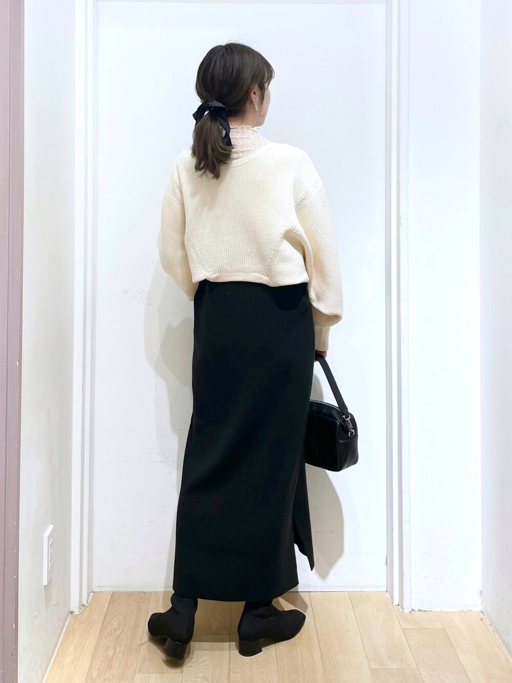 ブラック系のショルダーバッグ、ブラック系のパンプス、ホワイト系のカーディガン/ボレロを着用したレディースの春コーディネートの2枚目の写真