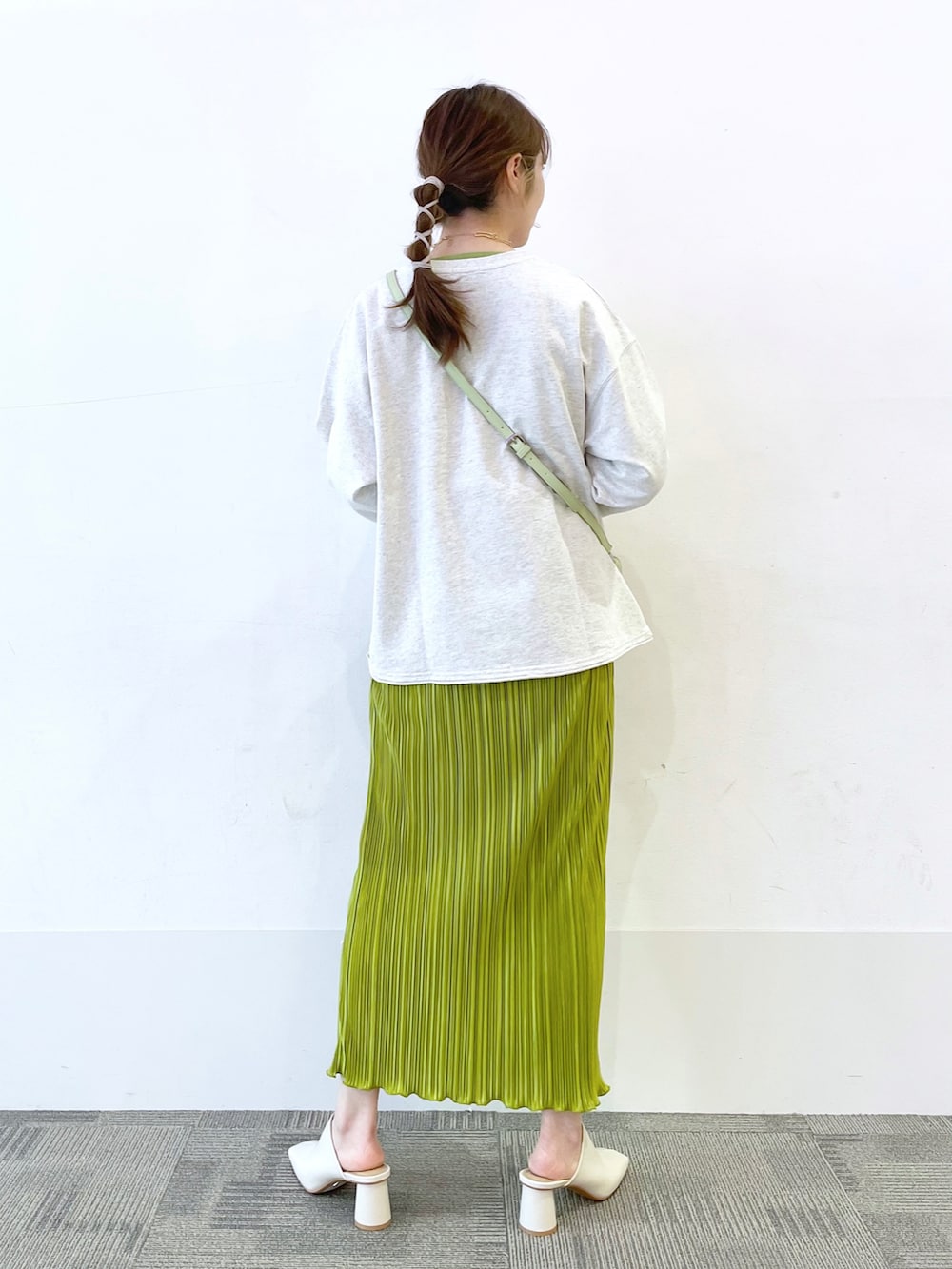 グリーン系のスカート、ホワイト系のサンダル、グレー系のスウェットを着用したレディースの春コーディネートの2枚目の写真