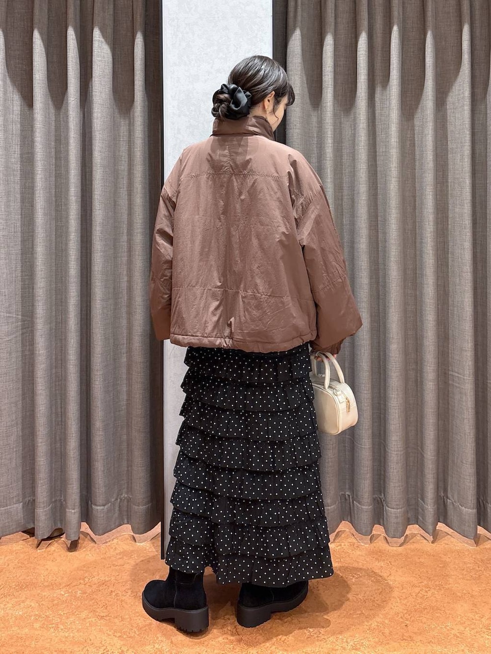 ブラウン系のその他アウター、その他のスカート、ホワイト系のボストンバッグを着用したレディースの冬コーディネートの4枚目の写真