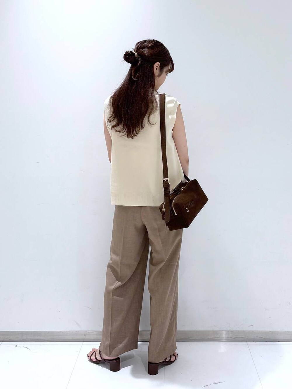 ホワイト系のTシャツ/カットソー、ブラウン系のサンダル、ベージュ系のスラックスを着用したレディースの夏コーディネートの4枚目の写真