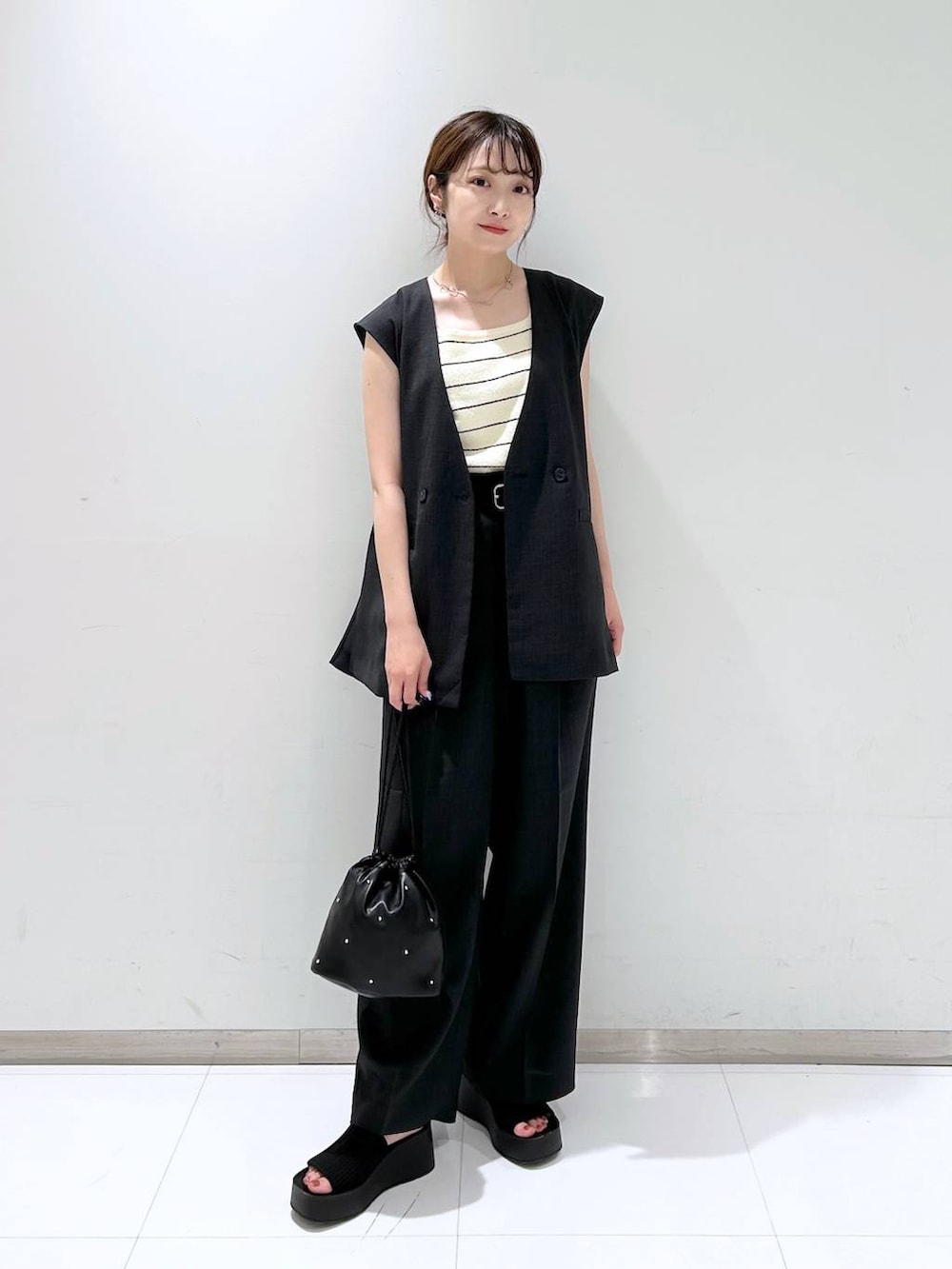 ブラック系のサンダル、ブラック系のショルダーバッグ、ホワイト系のタンクトップを着用したレディースの夏コーディネートの3枚目の写真