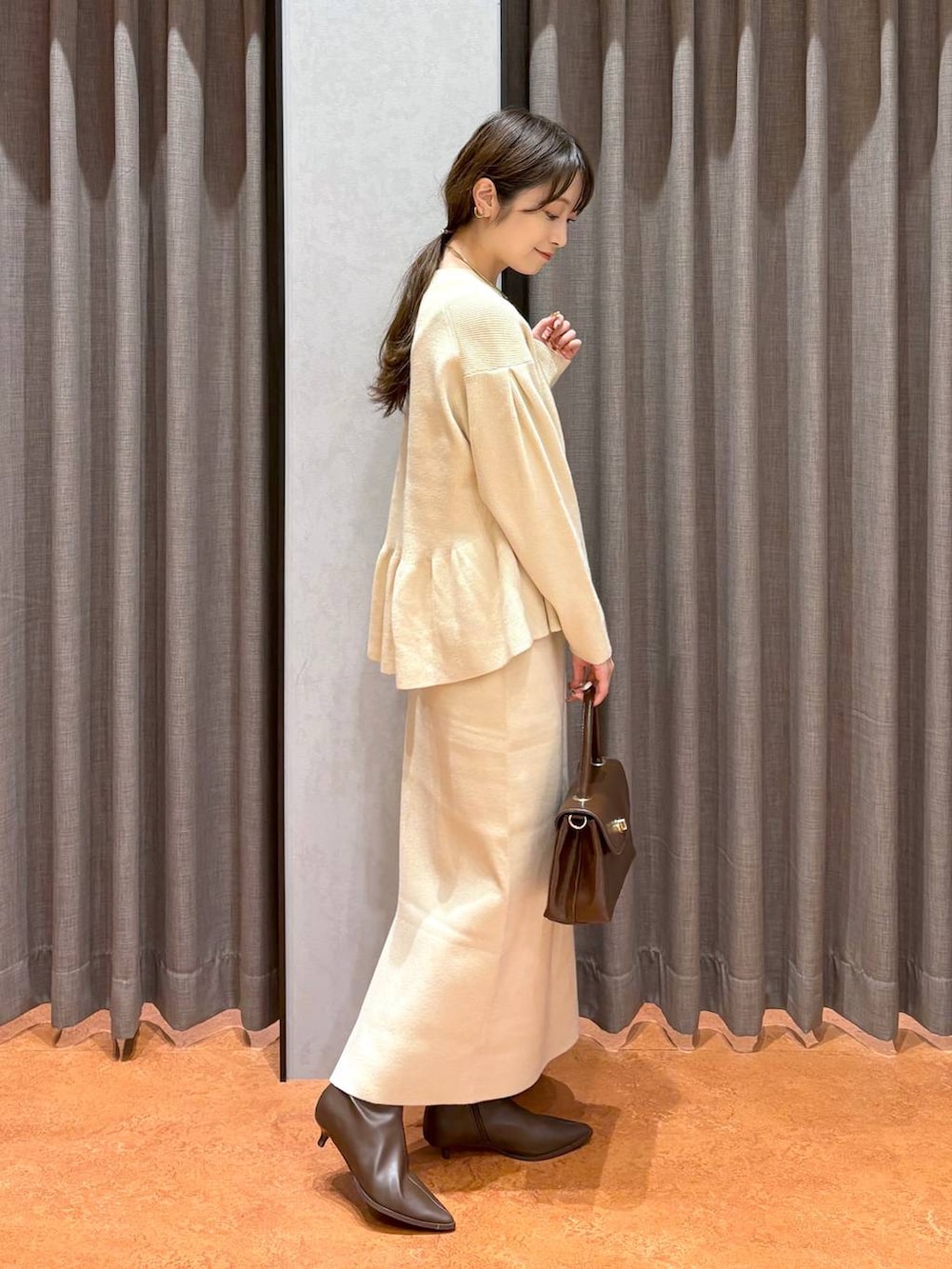 ブラウン系のボストンバッグ、ブラウン系のブーツ、ホワイト系のワンピースを着用したレディースの秋コーディネートの4枚目の写真