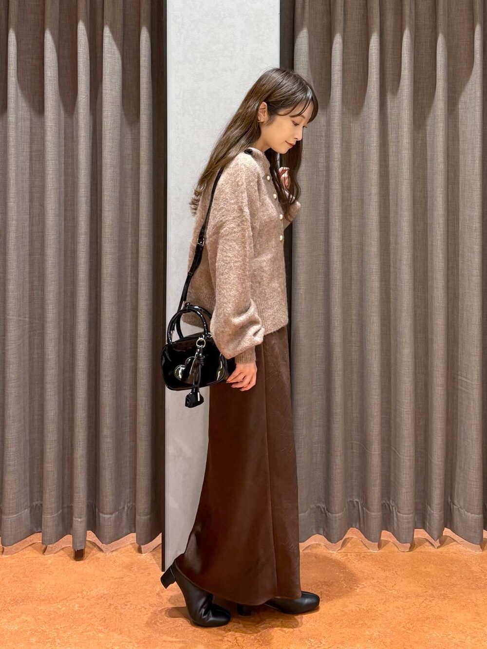 ブラウン系のスカート、ブラック系のボストンバッグ、ブラウン系のニット/セーターを着用したレディースの秋コーディネートの3枚目の写真