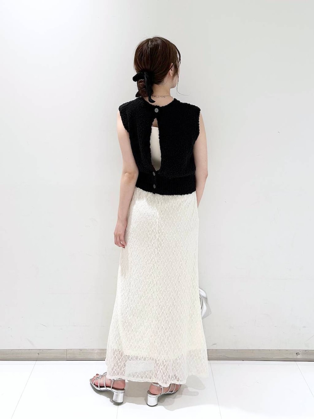 シルバー系のサンダル、ホワイト系のスカート、ブラック系のベストを着用したレディースの夏コーディネートの5枚目の写真