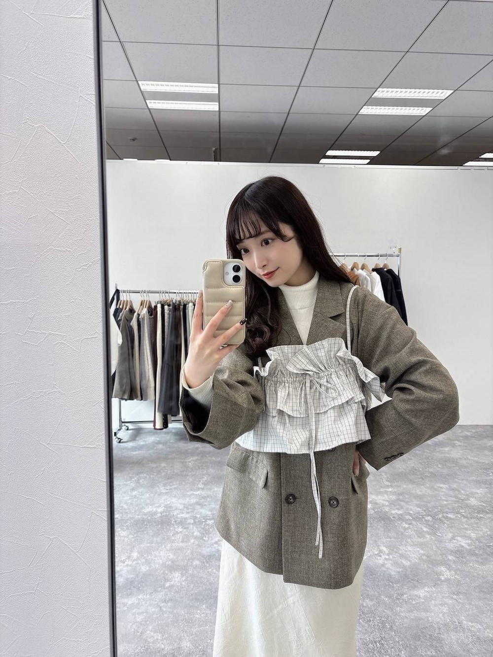 ホワイト系のスカート、ホワイト系のニット/セーター、ブラウン系のテーラードジャケットを着用したレディースの冬コーディネートの3枚目の写真