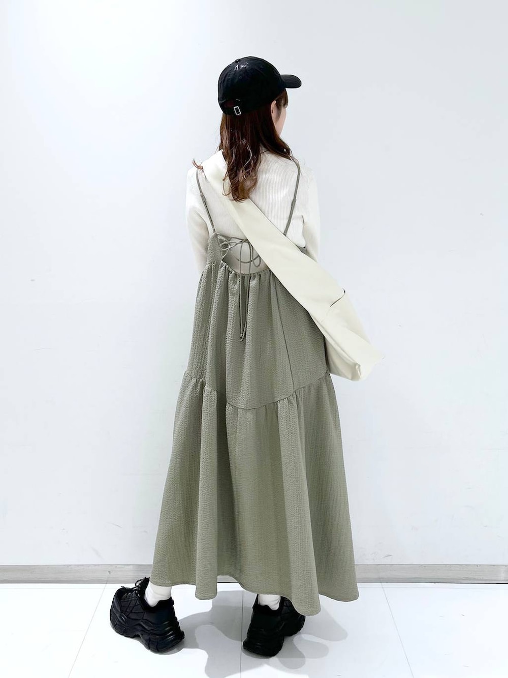 グリーン系のワンピース、ホワイト系のニット/セーター、ブラック系のスニーカーを着用したレディースの冬コーディネートの5枚目の写真