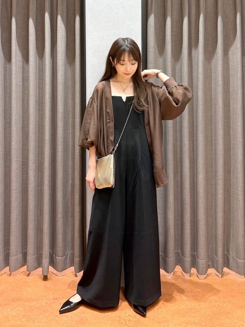 ゴールド系のショルダーバッグ、ベージュ系のキャミソール、ブラック系のワンピースを着用したレディースの秋コーディネートの2枚目の写真