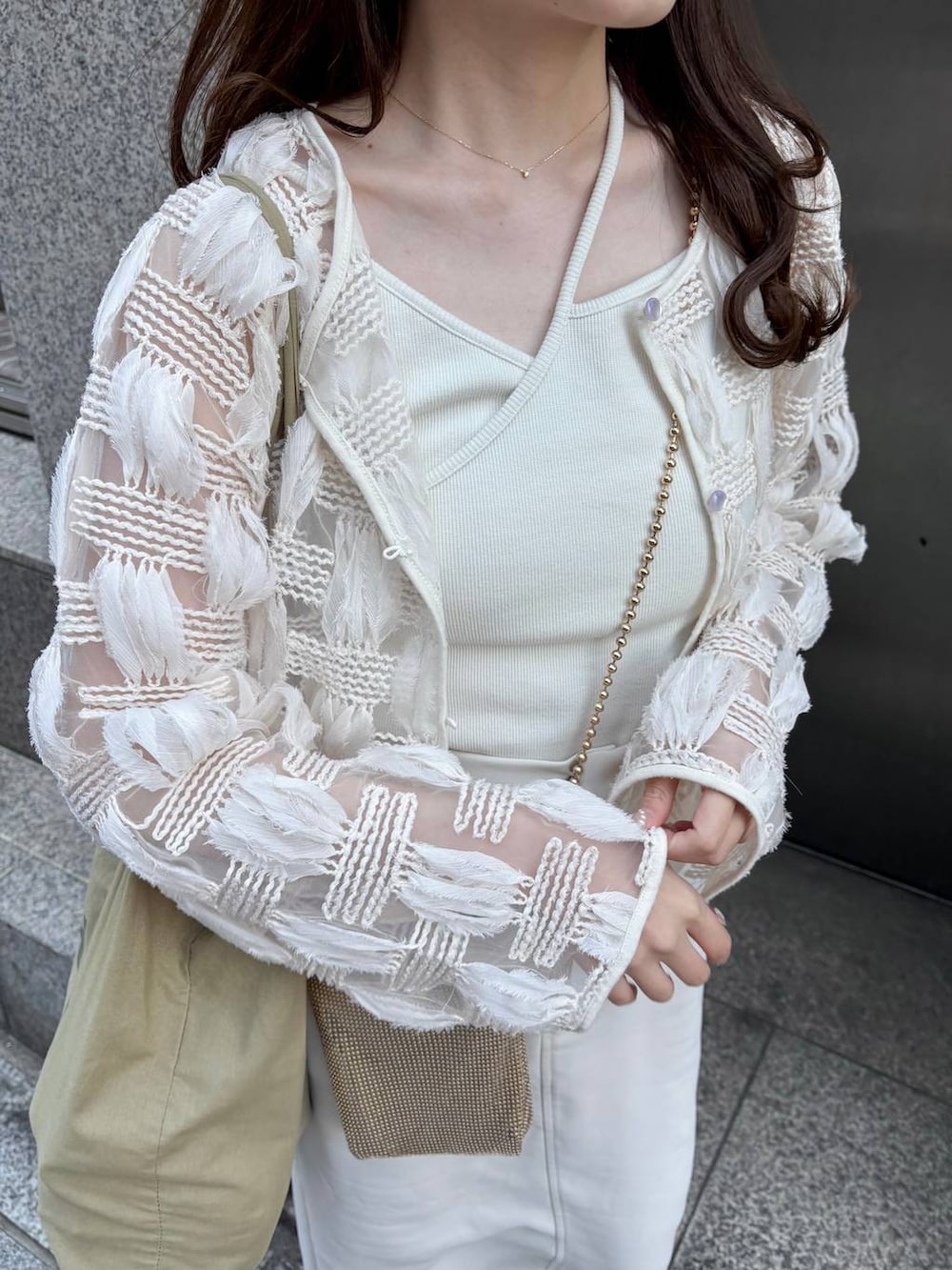 ゴールド系のショルダーバッグ、ホワイト系のパンプスを着用したレディースの春コーディネートの2枚目の写真