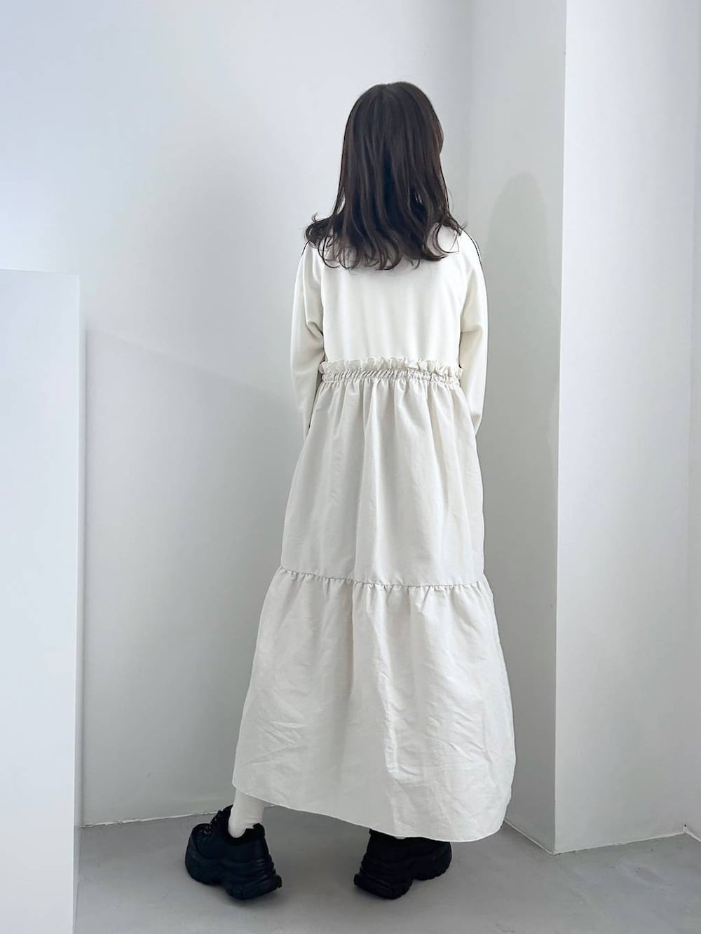 ブラック系のスニーカー、ホワイト系のワンピース、ゴールド系のイヤリングを着用したレディースの冬コーディネートの3枚目の写真