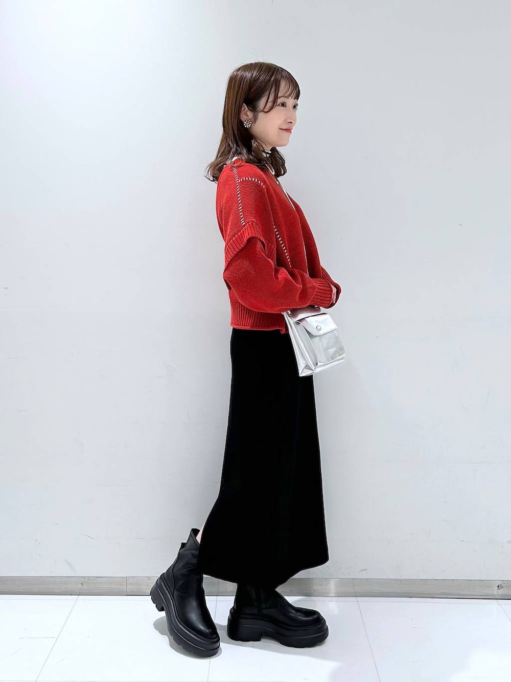 シルバー系のショルダーバッグ、グレー系のニット/セーター、レッド系のTシャツ/カットソーを着用したレディースの秋コーディネートの2枚目の写真