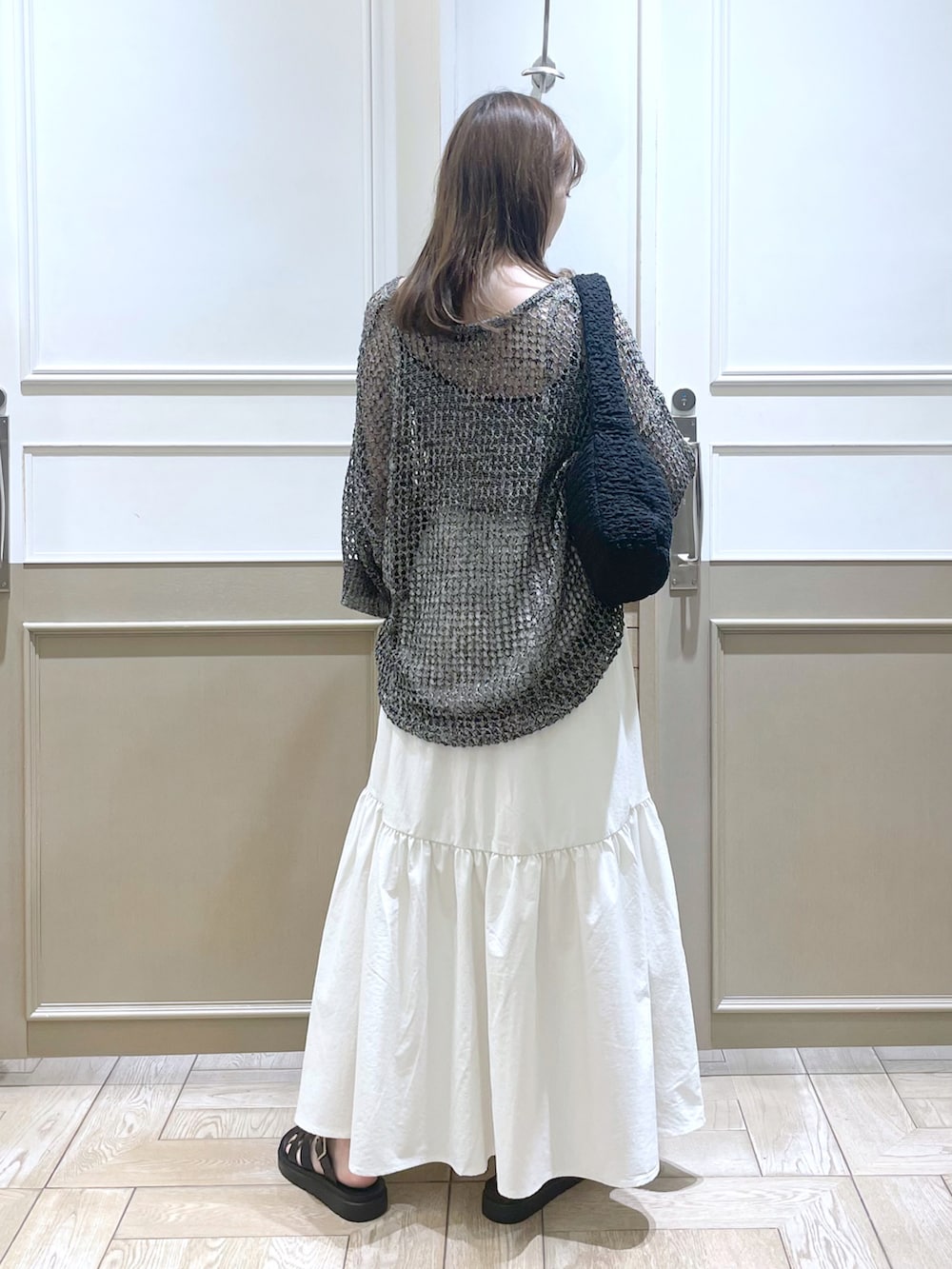 ブラック系のスニーカー、ホワイト系のスカート、ブラック系のニット/セーターを着用したレディースの夏コーディネートの2枚目の写真