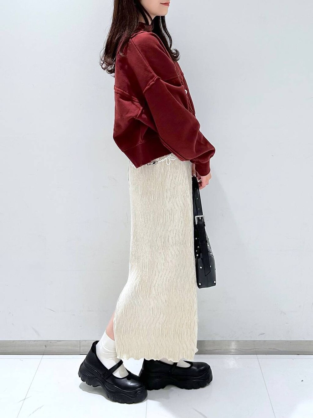 ブラック系のスニーカー、ホワイト系のスカート、ブラック系のショルダーバッグを着用したレディースの秋コーディネートの3枚目の写真