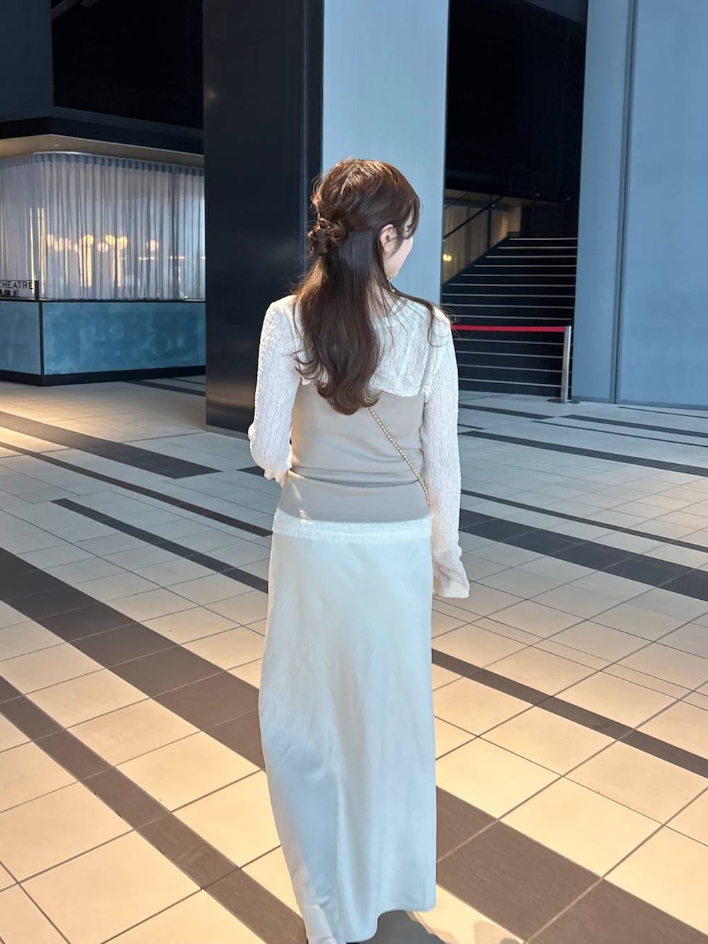 ゴールド系のショルダーバッグ、ホワイト系のスカート、ブラウン系のローファーを着用したレディースの春コーディネートの4枚目の写真