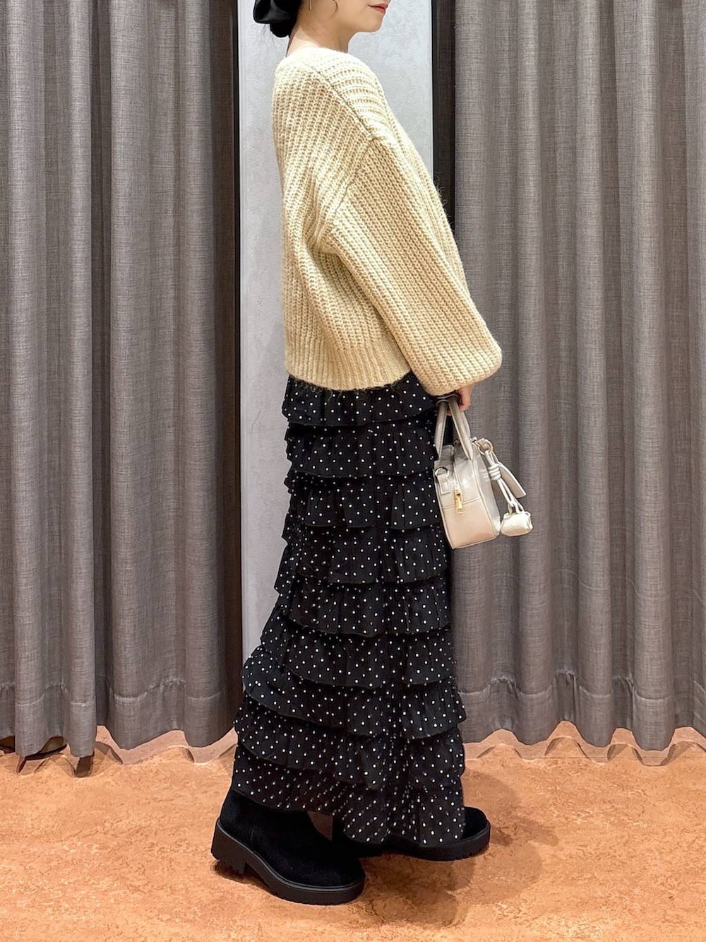 ブラウン系のその他アウター、その他のスカート、ホワイト系のボストンバッグを着用したレディースの冬コーディネートの7枚目の写真