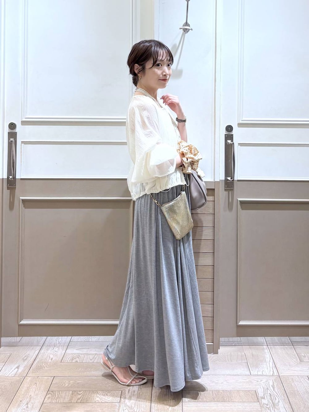 ゴールド系のショルダーバッグ、ホワイト系のサンダル、ホワイト系のブルゾンを着用したレディースの夏コーディネートの4枚目の写真