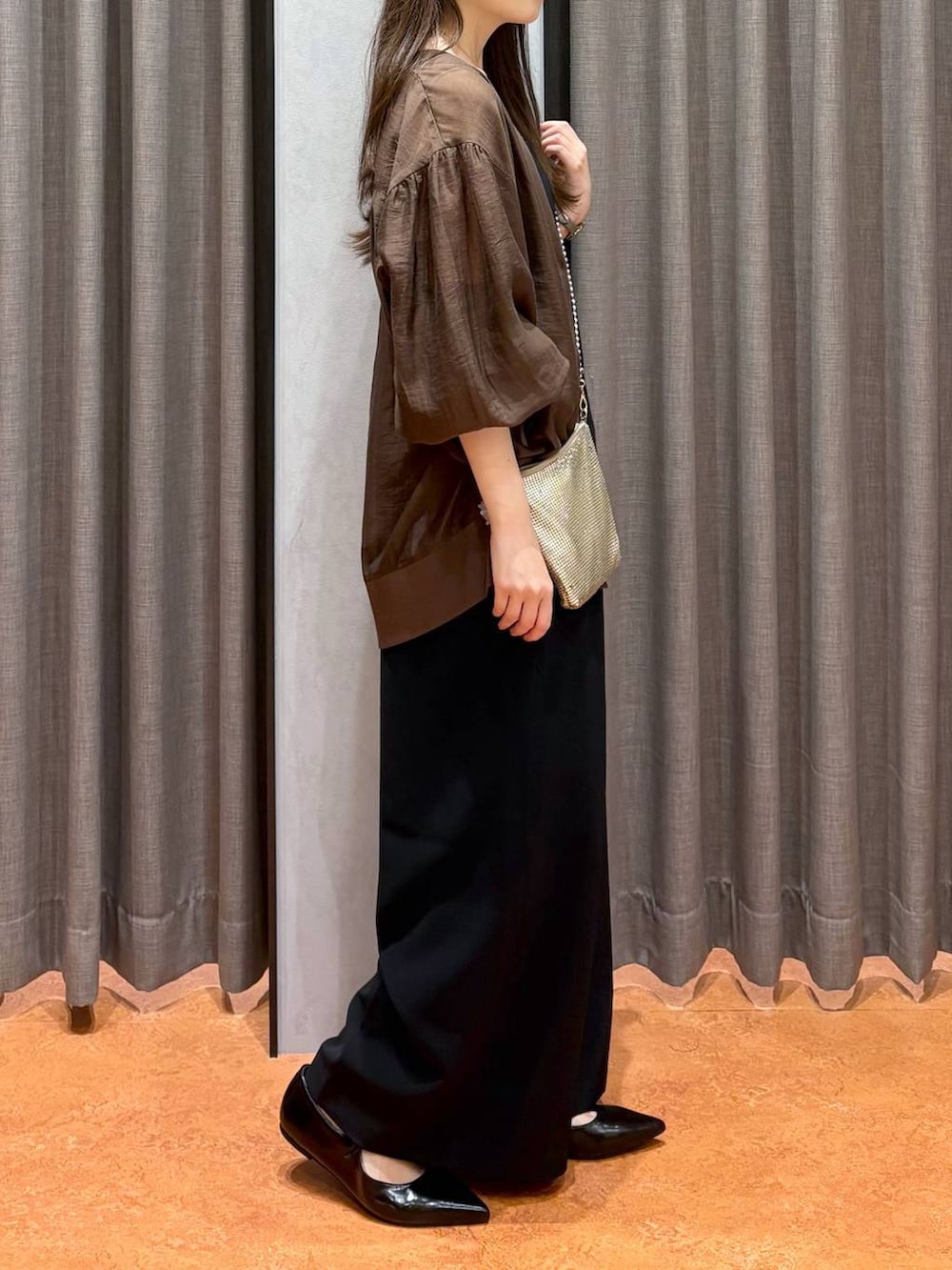 ゴールド系のショルダーバッグ、ベージュ系のキャミソール、ブラック系のワンピースを着用したレディースの秋コーディネートの3枚目の写真