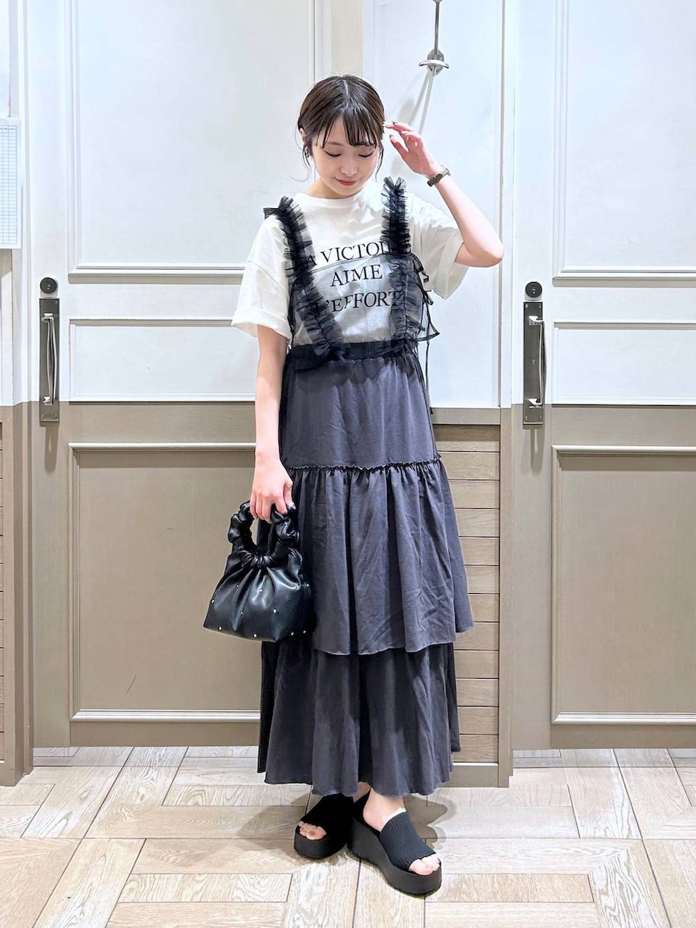 ブラック系のハンドバッグ、ブラック系のサンダル、ブラック系のベストを着用したレディースの夏コーディネートの3枚目の写真