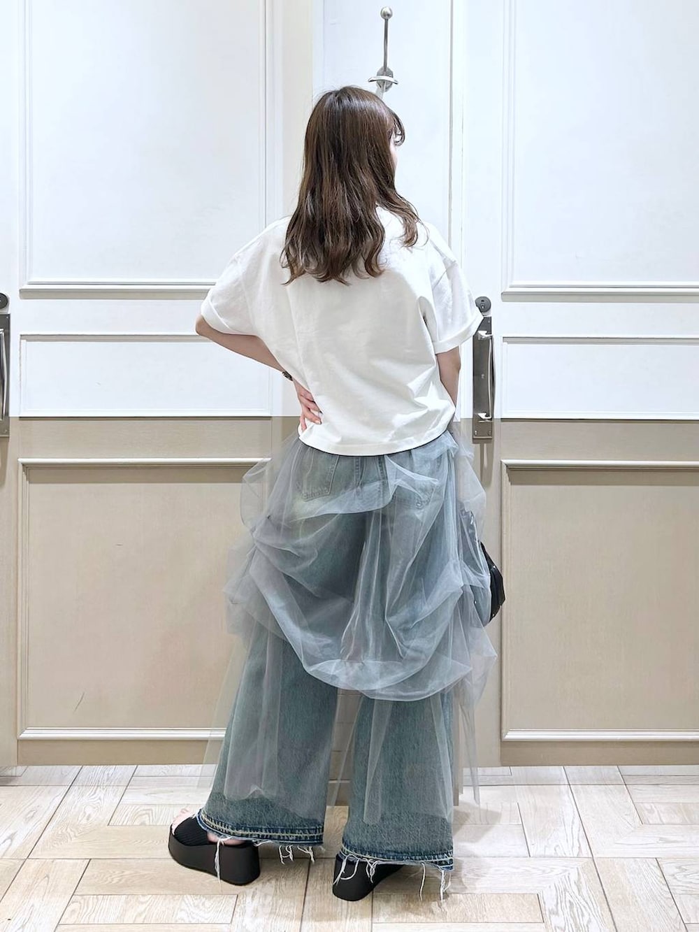 ブラック系のハンドバッグ、ブラック系のサンダル、ブルー系のデニムパンツを着用したレディースの夏コーディネートの4枚目の写真