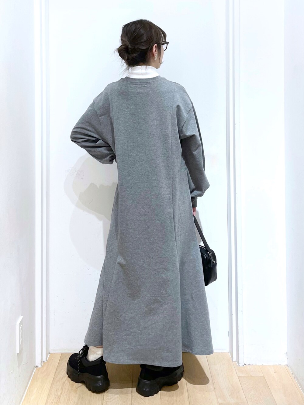 ブラック系のショルダーバッグ、ブラック系のスニーカー、グレー系のワンピースを着用したレディースの冬コーディネートの2枚目の写真