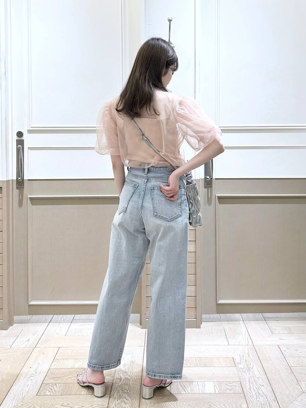 シルバー系のサンダル、ベージュ系のTシャツ/カットソー、ブルー系のデニムパンツを着用したレディースの春コーディネートの4枚目の写真