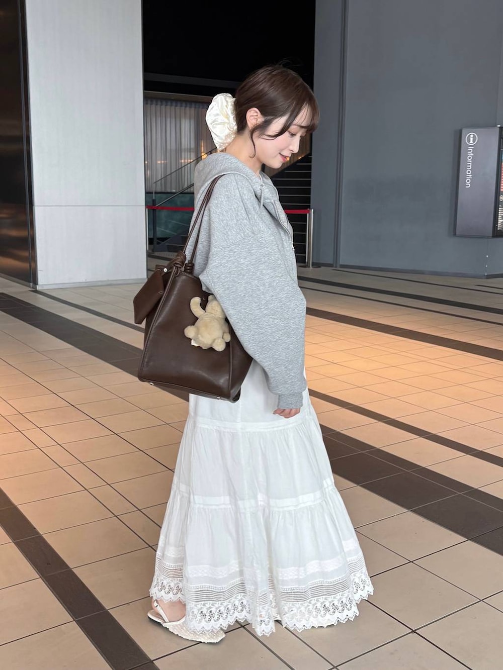 グレー系のパーカー、ブラウン系のトートバッグ、ホワイト系のパンプスを着用したレディースの春コーディネートの3枚目の写真