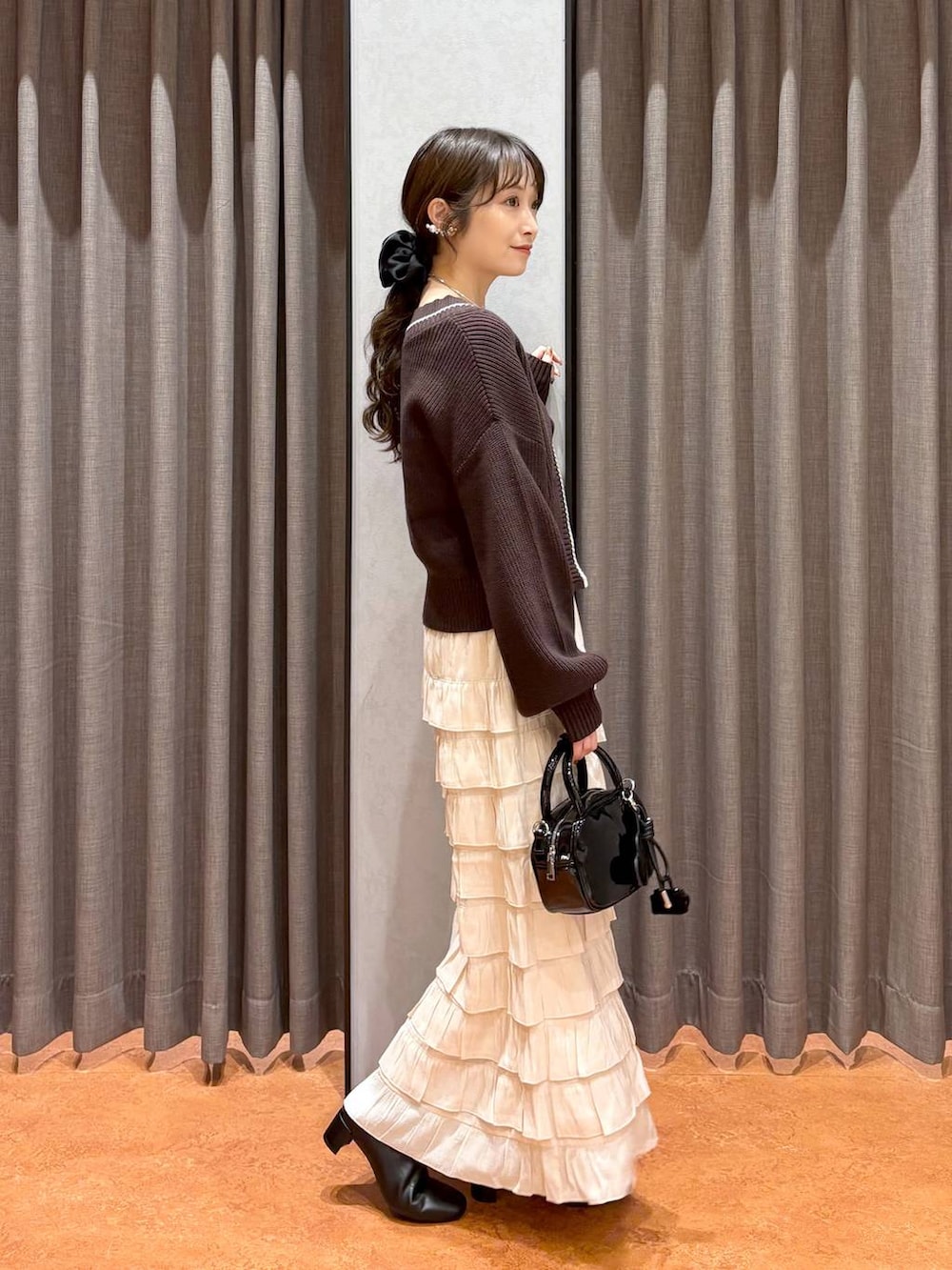 ベージュ系のキャミソール、ブラウン系のカーディガン/ボレロ、ブラック系のボストンバッグを着用したレディースの秋コーディネートの3枚目の写真