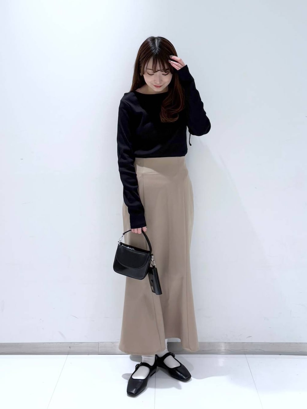 ブラック系のバレエシューズ、ブラック系のショルダーバッグ、ベージュ系のスカートを着用したレディースの冬コーディネートの3枚目の写真