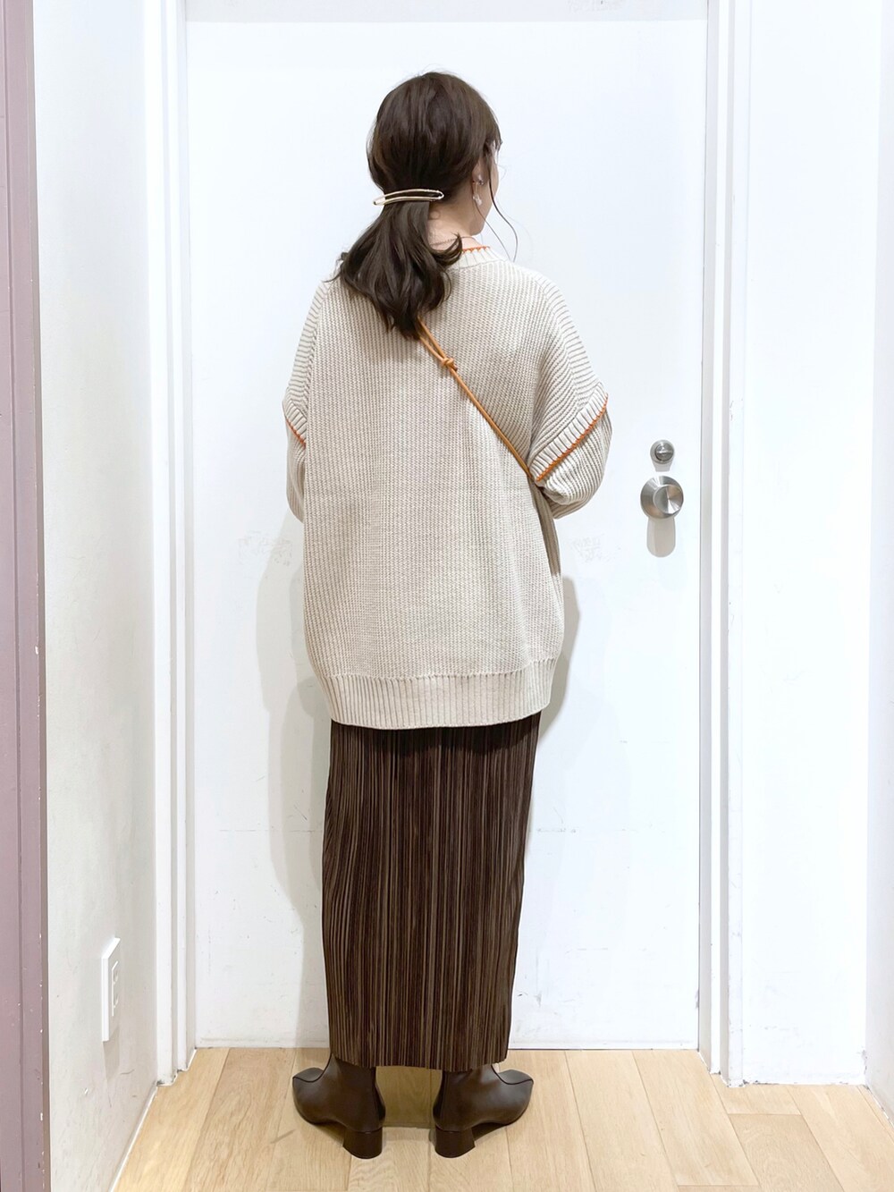 ブラウン系のニット/セーター、オレンジ系のショルダーバッグ、ブラウン系のスカートを着用したレディースの秋コーディネートの2枚目の写真