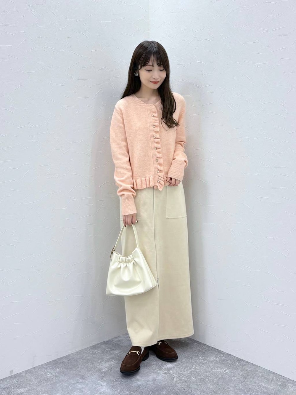 ホワイト系のスカート、ブラウン系のローファー、ホワイト系のショルダーバッグを着用したレディースの秋コーディネートの2枚目の写真