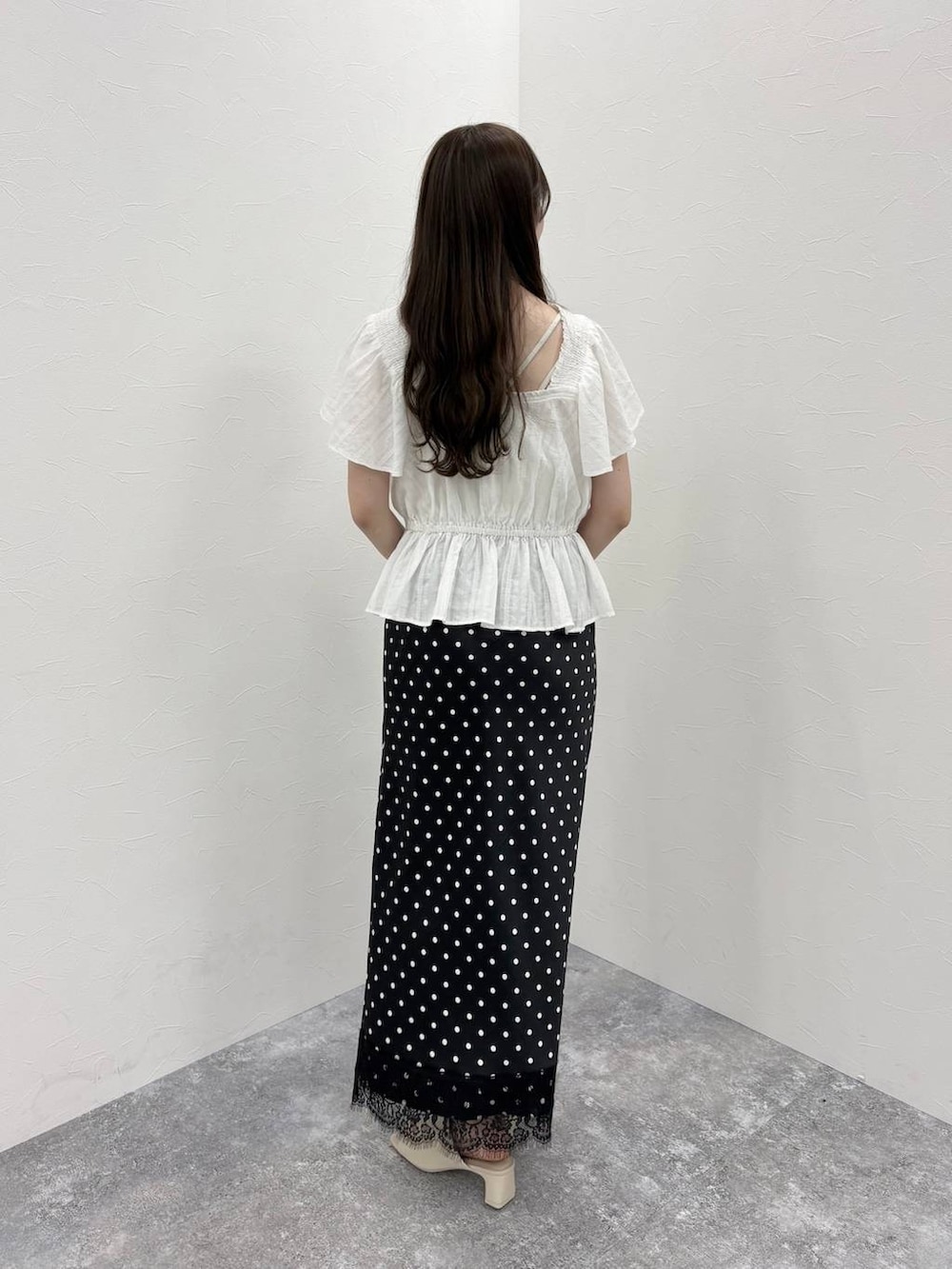 ホワイト系のTシャツ/カットソー、ホワイト系のサンダル、ブラック系のスカートを着用したレディースの春コーディネートの3枚目の写真