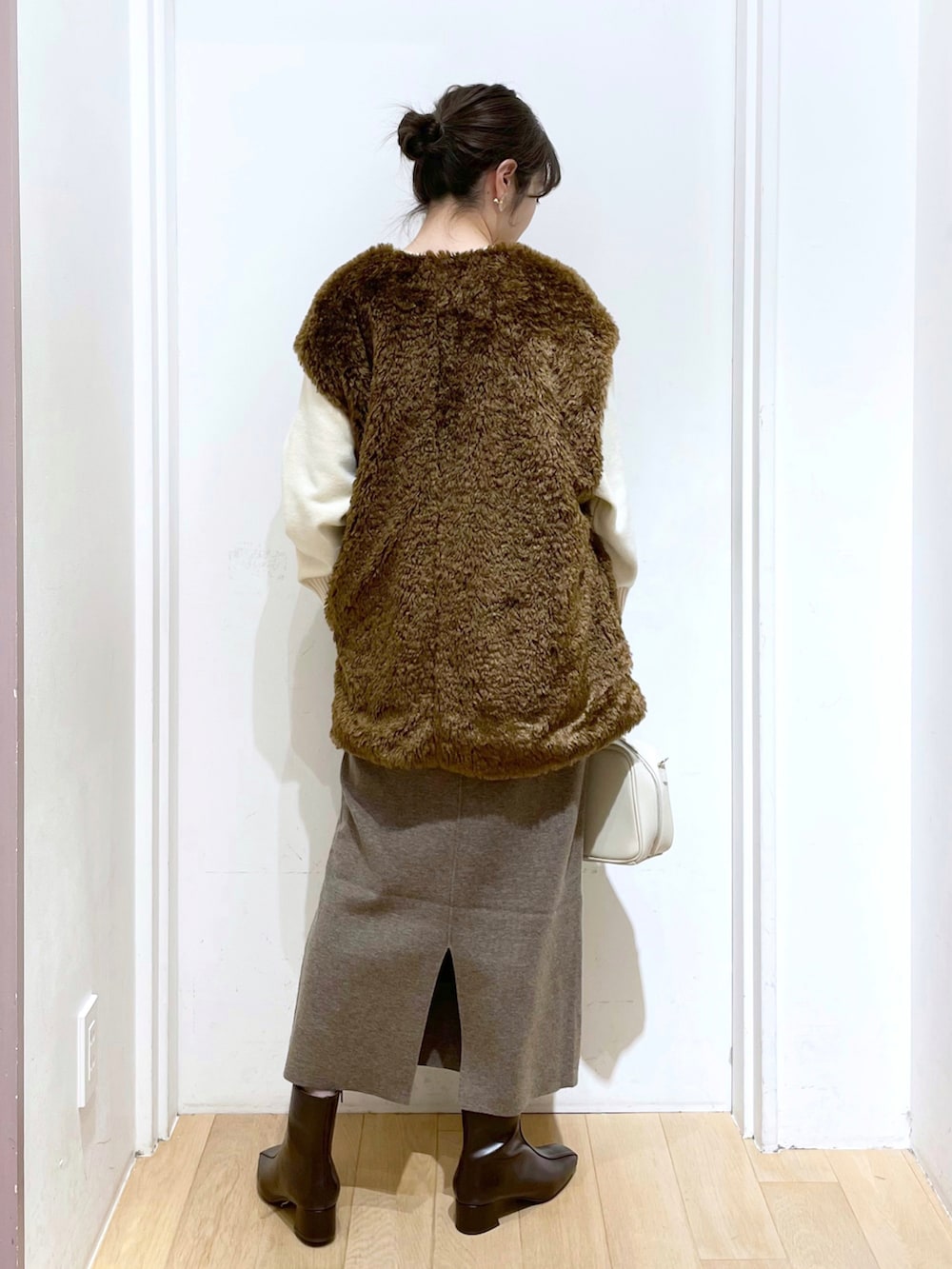 ホワイト系のショルダーバッグ、ブラウン系のブーツ、ベージュ系のスカートを着用したレディースの冬コーディネートの2枚目の写真