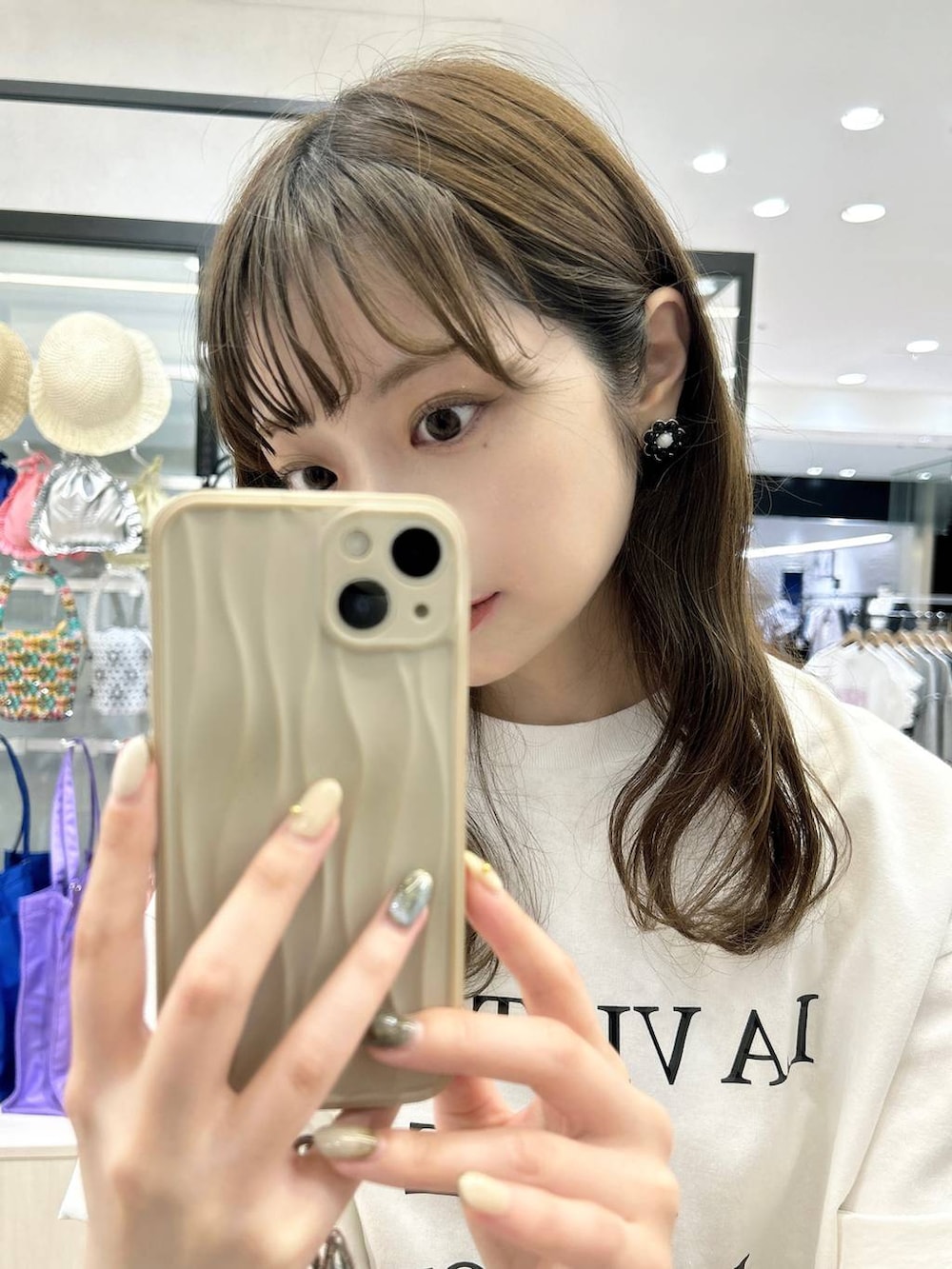 ベージュ系のスマホグッズ、ブラック系のイヤリングを着用したレディースの夏コーディネートの2枚目の写真