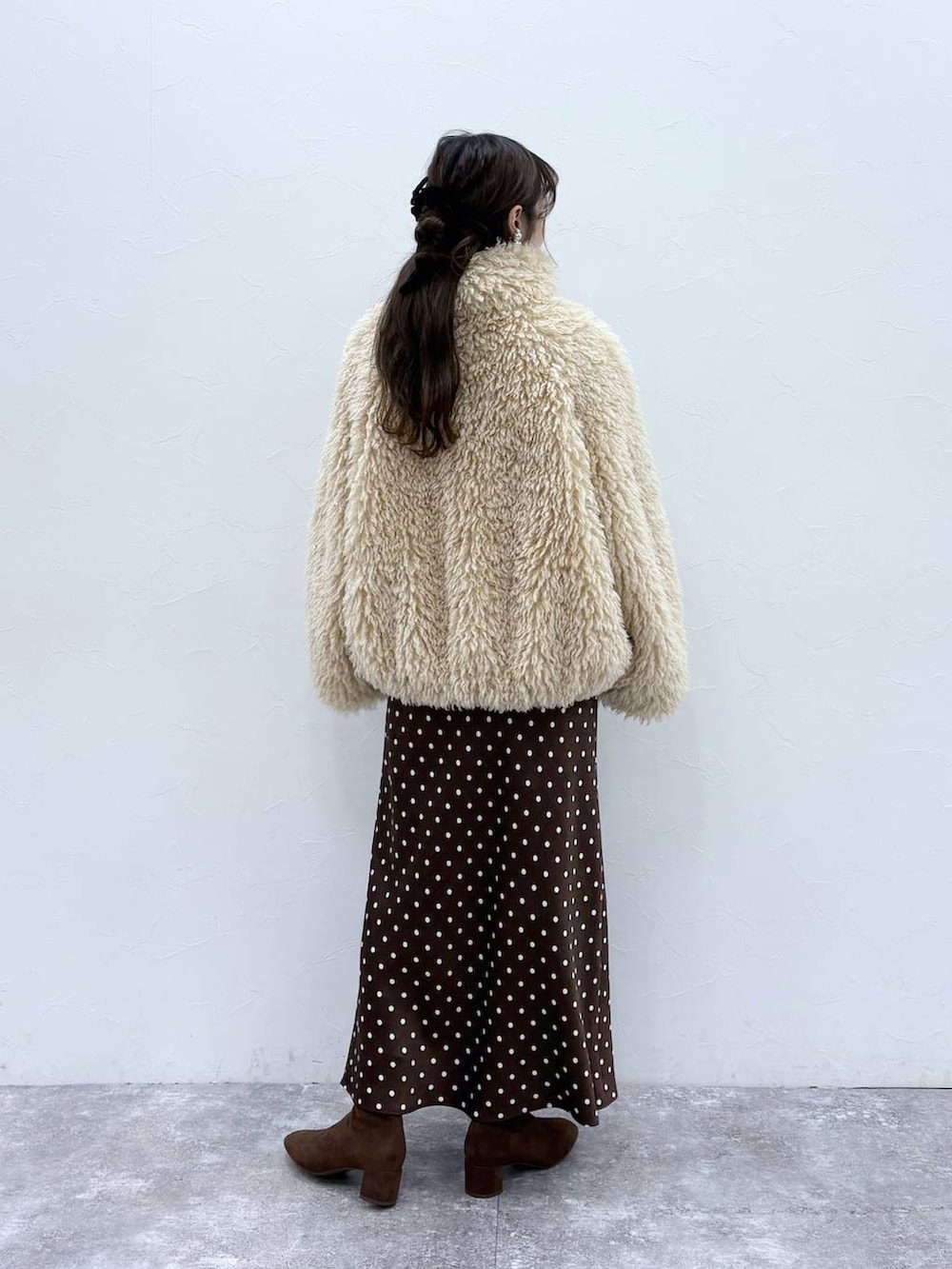 ブラウン系のスカート、ブラウン系のブーツ、ホワイト系のブルゾンを着用したレディースの秋コーディネートの4枚目の写真