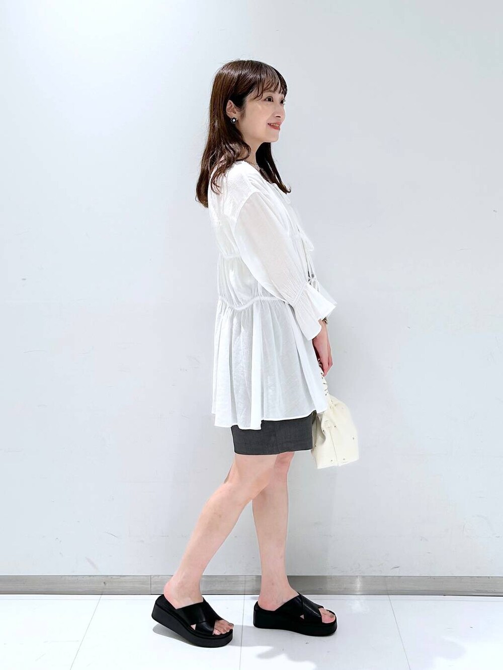 ベージュ系のハンドバッグ、ホワイト系のTシャツ/カットソー、ホワイト系のシャツ/ブラウスを着用したレディースの春コーディネートの5枚目の写真