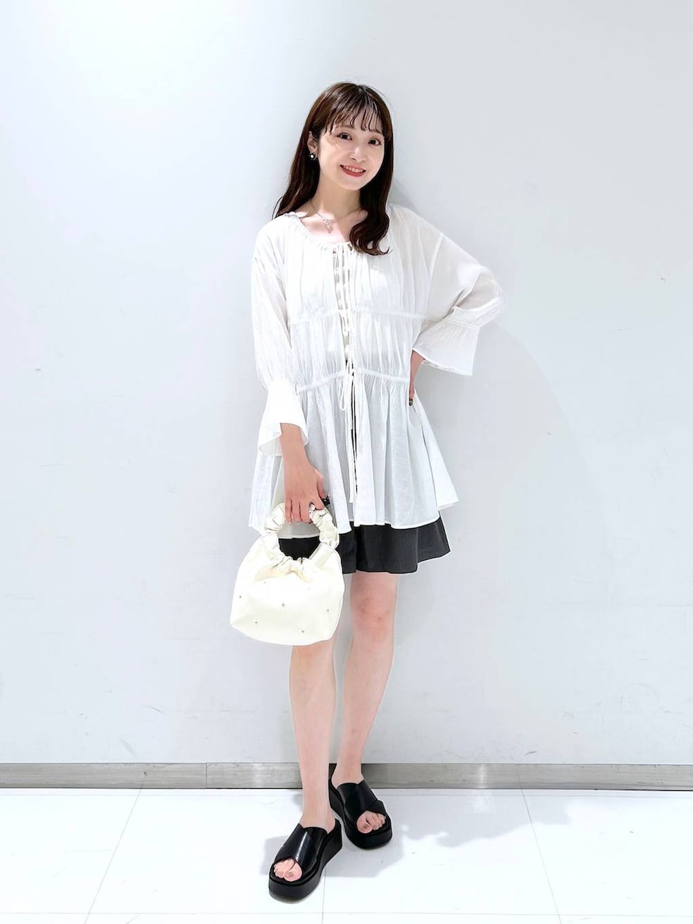 ベージュ系のハンドバッグ、ホワイト系のTシャツ/カットソー、ホワイト系のシャツ/ブラウスを着用したレディースの春コーディネートの2枚目の写真