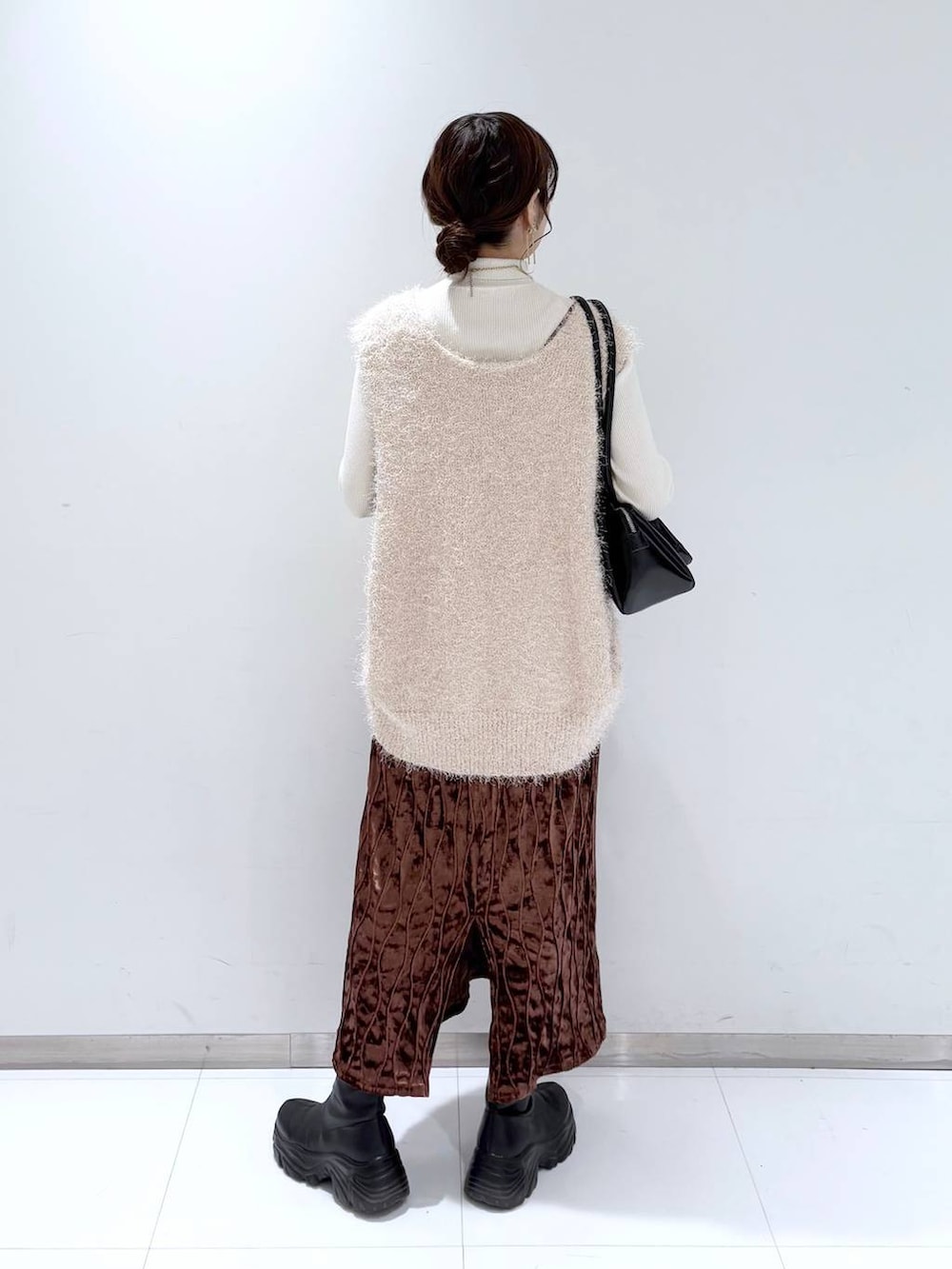 ホワイト系のニット/セーター、ブラック系のショルダーバッグ、ブラック系のブーツを着用したレディースの冬コーディネートの4枚目の写真