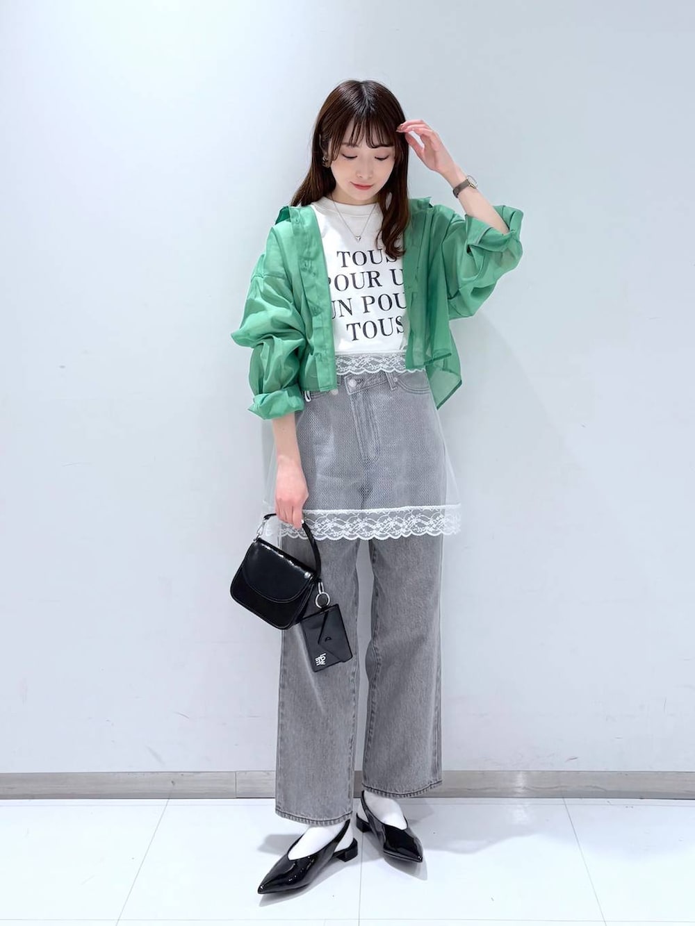 グリーン系のシャツ/ブラウス、グレー系のデニムパンツ、ブラック系のショルダーバッグを着用したレディースの春コーディネートの2枚目の写真