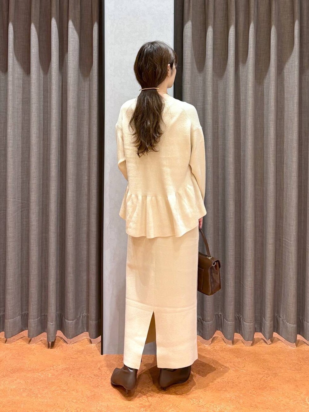 ブラウン系のボストンバッグ、ブラウン系のブーツ、ホワイト系のワンピースを着用したレディースの秋コーディネートの6枚目の写真